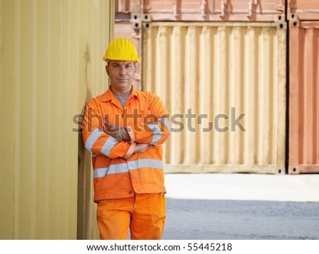 portrait of mid adult worker leaning on cargo container and looking at camera. Horizontal shape, front view, copy space