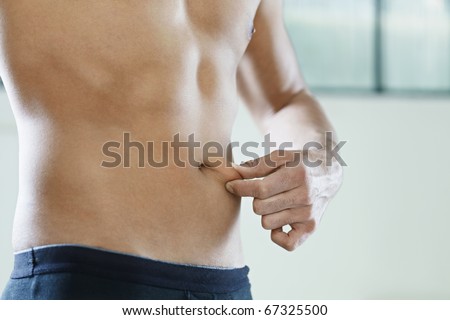 cropped view of young caucasian man measuring fat on belly. Horizontal shape, mid section, side view, copy space