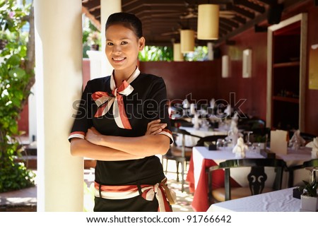 Portrait of attractive young asian woman working as waitress in exclusive restaurant. Waist up, front view