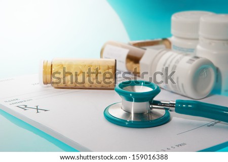 Empty medical prescription with a sthetoscope and medicine bottles  on blue reflective background