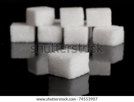 Lump sugar (sugar cubes) on black reflective background with shallow depth of field