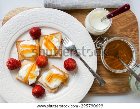 Delicious breakfast with bread, strawberries, yogurt and orange marmalade