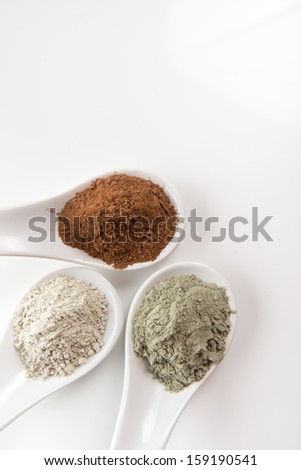 Three Different Clay Mud Powders, Red Mud, Bentonite and Green Clay in Ceramic Spoons