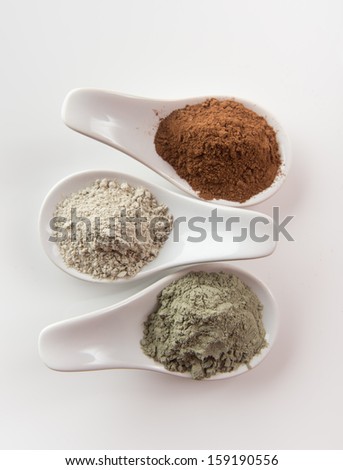 Three Different Clay Mud Powders, Red Mud, Bentonite and Green Clay in Ceramic Spoons