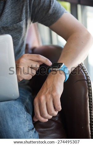 SEATTLE, USA - May 2, 2015: Man Checking Apple Watch While Working on Computer at Local Coffee Shop