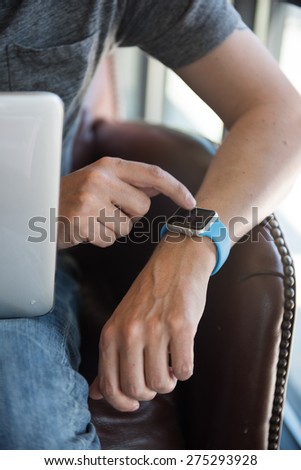 SEATTLE, USA - May 2, 2015: Man Checking Apple Watch While Working on Computer at Local Coffee Shop