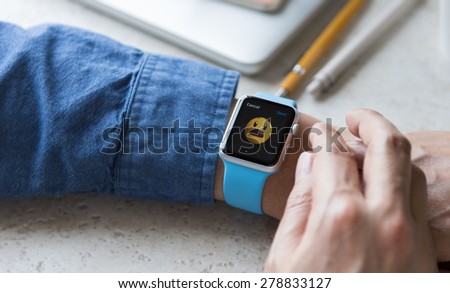 SEATTLE, USA - May 17, 2015: Man Wearing Sport Apple Watch with Blue Rubber Band. Not Happy Face Emoji Displayed.