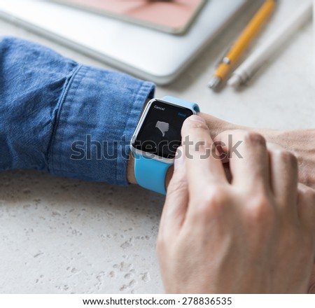 SEATTLE, USA - May 17, 2015: Man Wearing Sport Apple Watch with Blue Rubber Band. Thumb Down Emoji Displayed.