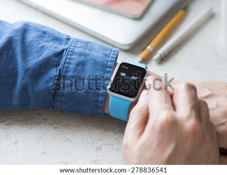 SEATTLE, USA - May 17, 2015: Man Wearing Sport Apple Watch with Blue Rubber Band. Blue Heart Emoji With Wings Displayed.
