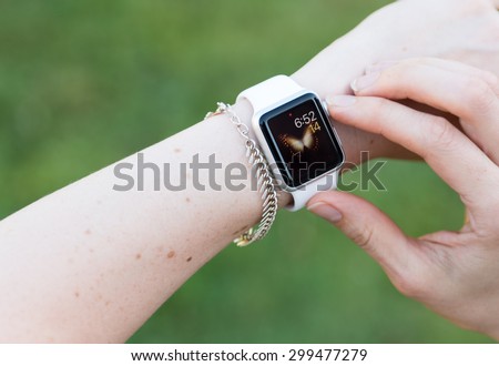 SEATTLE, USA - July 24, 2015: Woman Using Apple Watch While Outside. Checking Time with App.