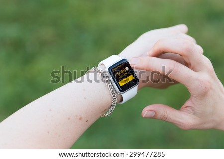 SEATTLE, USA - July 24, 2015: Woman Using Apple Watch While Outside. Using Activity App to Track Distance and Calories Per Workout.