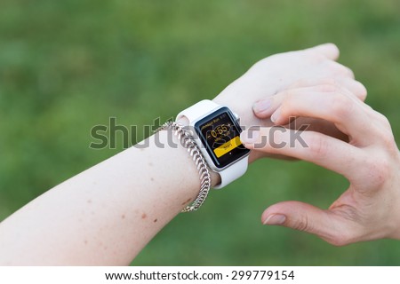SEATTLE, USA - July 25, 2015: Woman Using Apple Watch While Outside. Using Activity App to Track Distance and Calories Per Workout.
