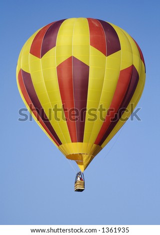 A purple, red, and yellow striped hot air balloon drifts silently across a clear blue sky.