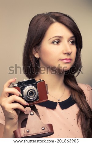 Young hipster woman make a photography with old camera. Warm color toned image.