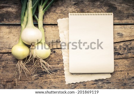 Warm color toned series of Vegetables with recipe book on wooden table. Old wood background. Menu background. Onion