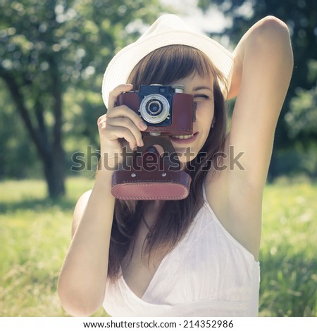 Young beautiful woman posing with old film camera in summer park. Toned image.