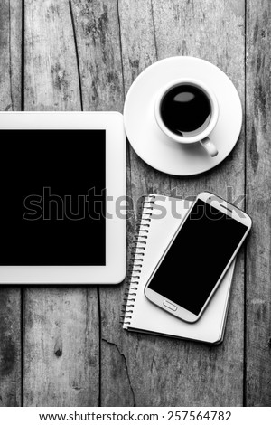 Mock up of mobile workplace. Digital tablet with smartphone and cup of coffee. Black and white image