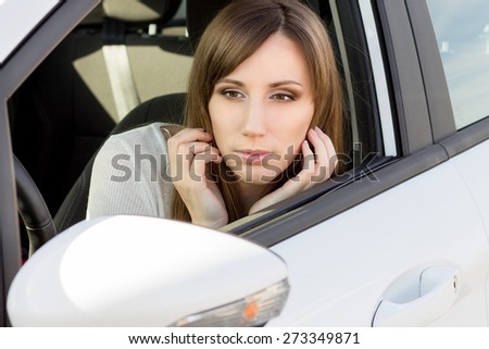Beauty caucasian girl check up her make-up. Young pretty woman in white car looking in the mirror