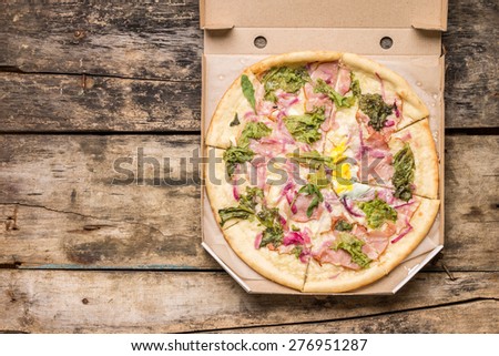 Restaurant menu and recipe background. Tasty pizza in carton box on wooden table.