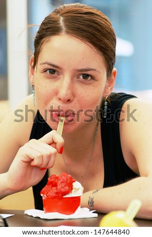 young caucasian  brunette woman portrait in cafe eating ice-cream with spoon in mouth