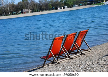 three orange folding chairs by blue water