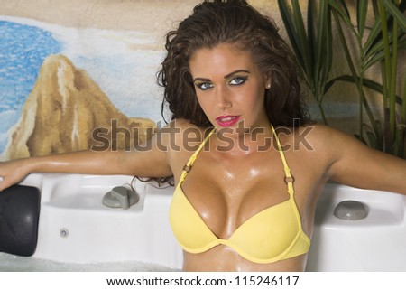 Sexy beautiful brunette woman in the jacuzzi in yellow bikini