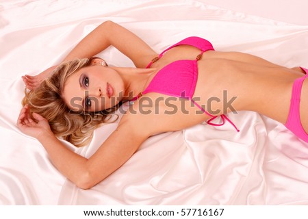Sexy woman in pink bikini laying on white blanket