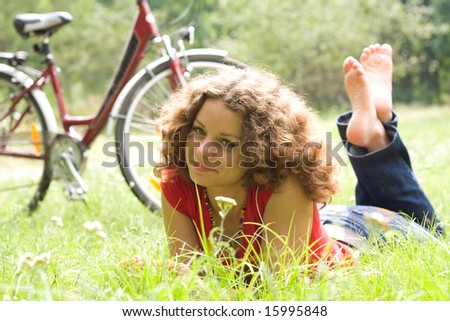 beautiful girl with a bicycle rests on a grass