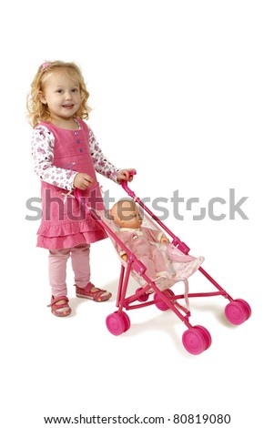 Little girl dressed in pink pushing a doll in a pram