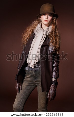 young fashion model in hat with scarf posing in the studio
