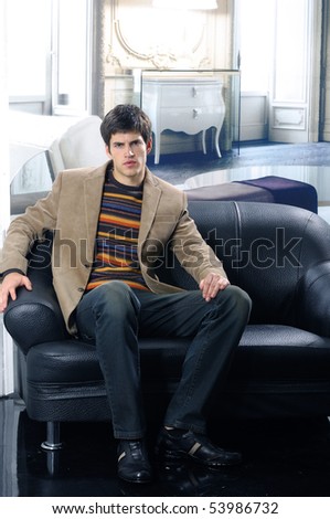 handsome young male model at interior seated on the couch