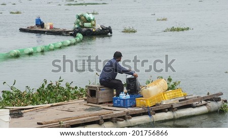 KAOSHION CITY, KAOSHION, TAIWAN - JUNE 28, 2014: Taiwanese sanitation workers working on a river, trying to take water hyacinth into the net in order to discard them after the collecting operation.