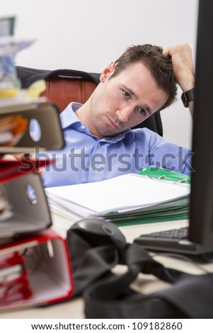 Office businessman at his desk full of documents, showing an overwhelmed expression.
