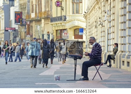 BUCHAREST, ROMANIA - SEPTEMBER 06: Unidentified busker plays the cimbalom and receives money rewards from tourists on September 06, 2013 in historical center of Bucharest, Romania.