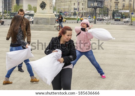 BUCHAREST, ROMANIA - APRIL 5: Group of unidentified cheerful women fight with white pillows and have fun on International Pillow Fight Day on April 5, 2014 in University Square, Bucharest, Romania.