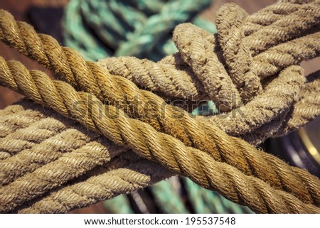 Close-up of used vintage marine ropes with nautical knot on old sailing vessel.