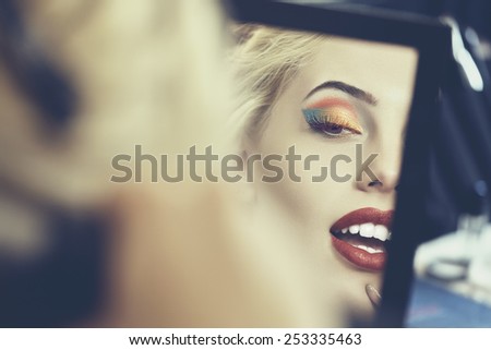 Detail of beautiful sensual woman face in a mirror. Beauty makeup and cosmetics treatment. Shallow depth of field and mate color grading.
