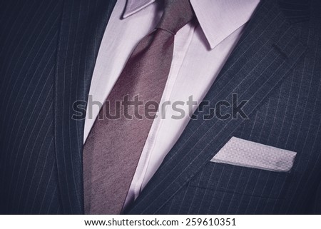 Closeup of elegant formal business suit with dark grey jacket with handkerchief in the pocket, shirt and necktie.