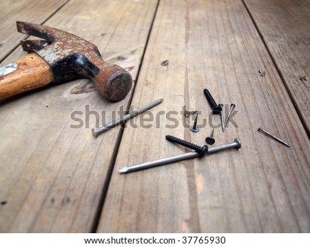 A old hammer nails, screws and wood tacks, on wood deck beams.