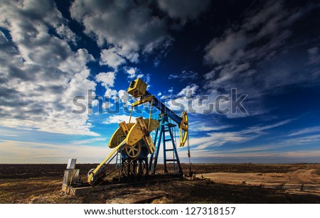 Operating oil well profiled on dramatic cloudy sky