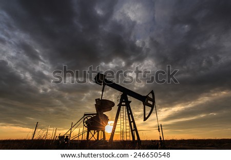 Industrial scenery with oil and gas well pump, profiled on sunset sky