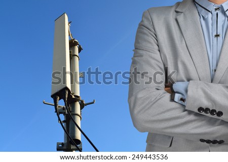 Technician Manager with Communication tower with micro cellular site under the blue sky.