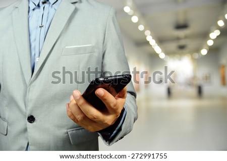 Business Man using Mobile Phone in the Art Gallery Hall as Wireless Technology concept. Selective Focus on Hand and Phone.