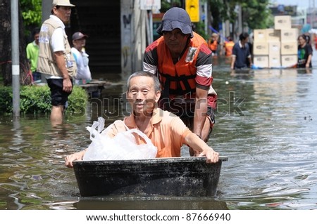 BANGKOK - OCTOBER 29: An unidentified volunteer uses a black basin as a boat to rescue an old man from his house during Thai flood crisis on October 29, 2011 in Bangkok, Thailand.