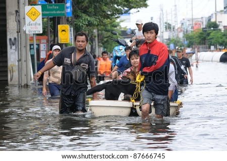 BANGKOK - OCTOBER 29: Unidentified victims use a boat to rescue flood victims, woman and her pet, on October 29, 2011 on Charansanitwongse Road , Bangkok, Thailand.