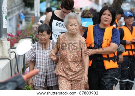 BANGKOK - OCTOBER 29: Rescue team bring old women flood victims to safe place during Thai flood crisis on October 29, 2011 in Bangkok, Thailand. The area is located on the west side of the Chaopray