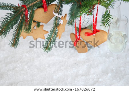 Tree dressed gingerbread ornaments. Christmas toys made ??with their own hands. Cookies on fir branches. Gingerbread, spruce, champagne glasses and snow on a white background