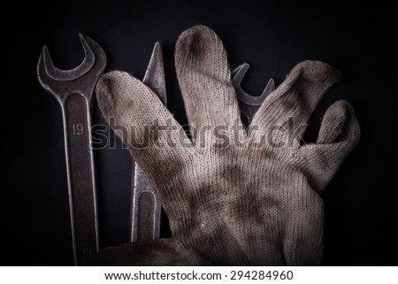 Wrenches and dirty glove on a black background concept of manual work