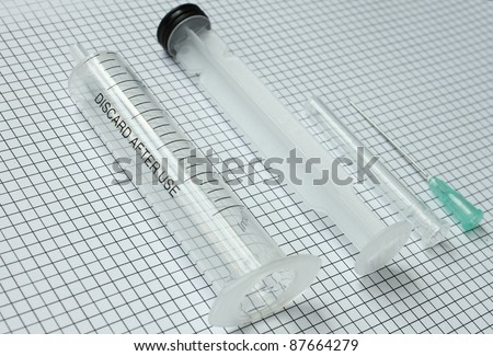 disassembled medical syringe on graph paper. the concept of mechanics, physics, engineering.