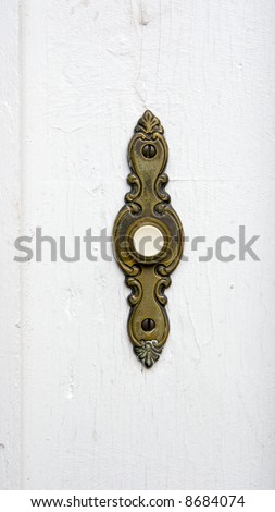 Color DSLR image of antique, weathered bronze electric door bell on a chipped white paint background. Vertical with copy space for text.